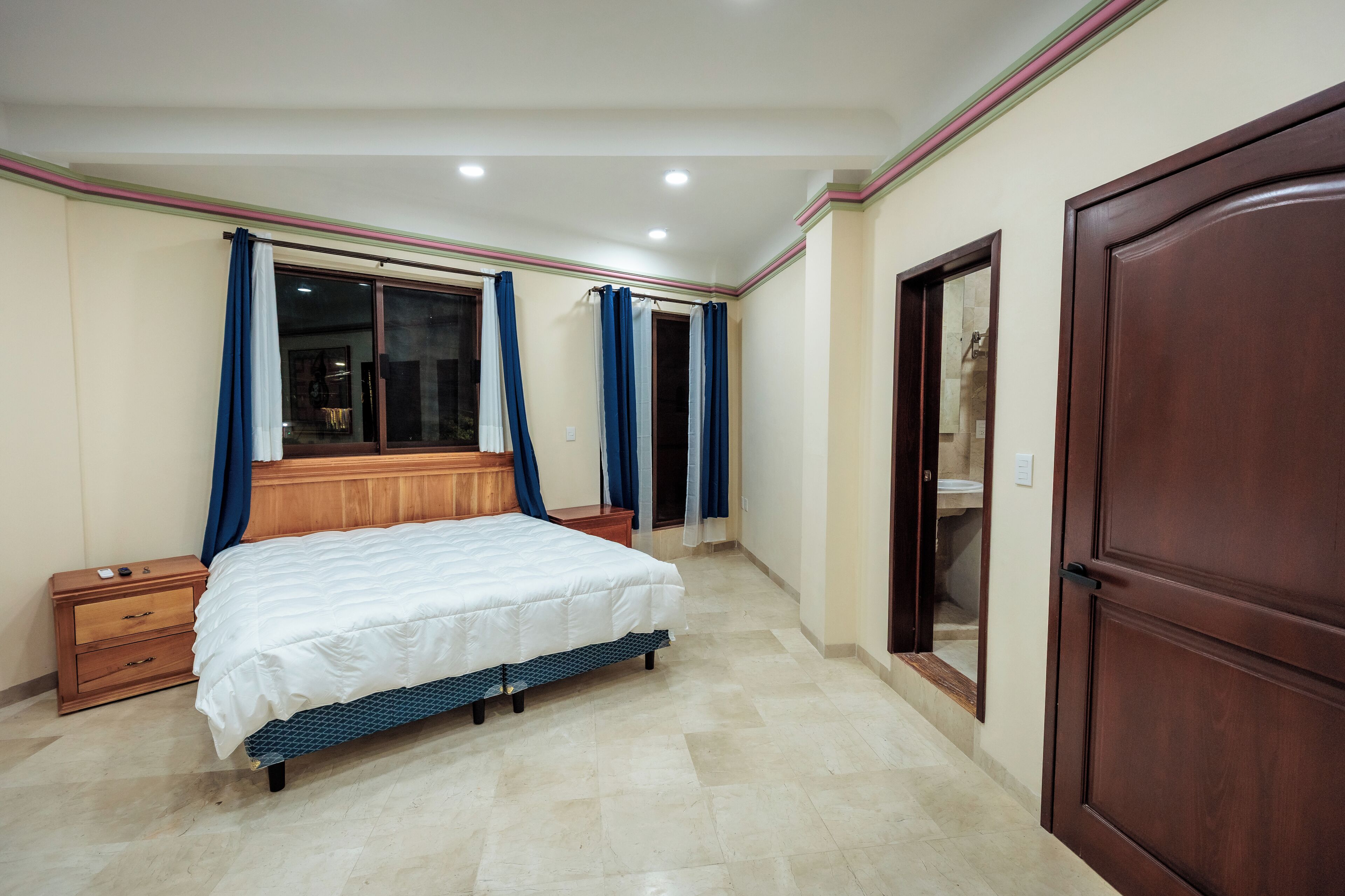 A bedroom with a bed, wooden nightstand, and a wardrobe.