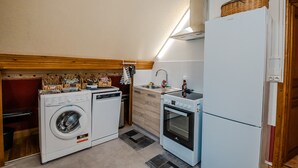 A compact kitchen with a washing machine, oven, and refrigerator. - 'Courseulles Comme À La Maison' Apartment with Private Terrace and Wi-Fi (Courseulles-sur-Mer)