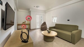 A modern living room with a green sofa, a wooden coffee table, and a TV mounted on the wall. - Hotel Delfin (Omišalj)
