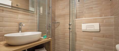 Ein modernes Badezimmer mit einem großen weißen Waschbecken, einer Duschkabine aus Glas und einer Toilette.