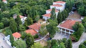 An aerial view of a residential area with multiple houses, each featuring red-tiled roofs and surrounded by greenery. - Hotel Delfin (Omišalj)