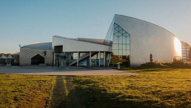 A modern building with a unique geometric design, large glass windows, and a prominent entrance. - La Voile de Nacre – Ground Floor Apt, 50m from Beach, Bernières-sur-Mer (Bernières-sur-Mer)