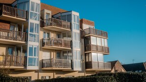 A multi-story residential building with balconies, large windows, and a brick facade. - La Voile de Nacre – Ground Floor Apt, 50m from Beach, Bernières-sur-Mer (Bernières-sur-Mer)