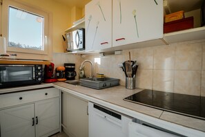 Een keuken met een magnetron, koffiezetapparaat, spoelbak en diverse keukengerei.