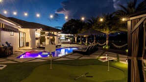 A backyard with a swimming pool, lounge chairs, a barbecue area, and a small putting green. - Private Resort Stay - Insta-Worthy Miami Vacation (Miami)