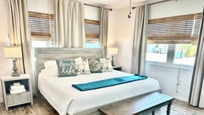 A bedroom with a bed, bedside tables, a bench, and a window with curtains. - Hidden Haven / Private Pool & Hot Tub (Holmes Beach)