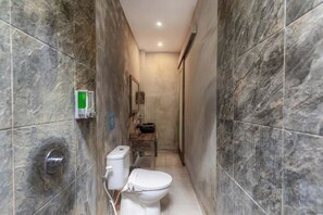 A narrow bathroom with a toilet, a sink, and a shower area.