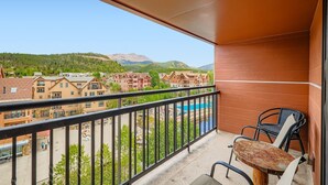 Un balcón con vista a una zona turística, que incluye edificios y una piscina.