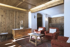 A cozy room with wooden paneling, a wooden cabinet, a table, and two armchairs.