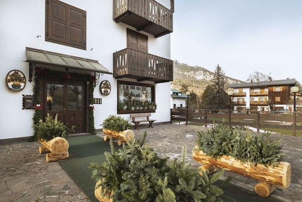 A building with a stone-paved courtyard, wooden benches, and Christmas trees.
