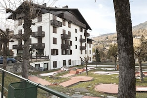A multi-story hotel with balconies, a parking area, and a view of the surrounding landscape.
