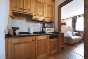A kitchen with wooden cabinets, a microwave, a kettle, and a dishwasher.