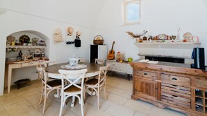 Uma cozinha rústica com uma mesa de jantar de madeira, cadeiras brancas e um armário embutido de madeira.