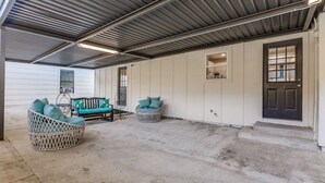 A covered outdoor area with two wicker chairs, a bench, and a door. - Charming house in Fort Worth walking distance to TCU (Fort Worth)