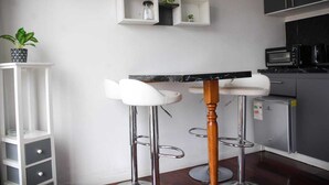 A modern kitchen with white bar stools, a marble countertop, and built-in appliances.