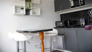A modern kitchen with a black countertop, white bar stools, and grey cabinets.