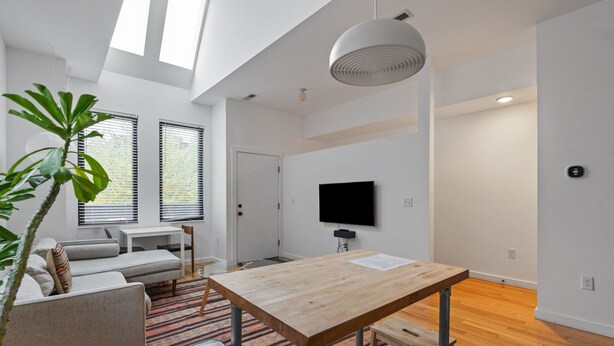Una sala moderna con sofá, mesa de comedor y una planta grande.