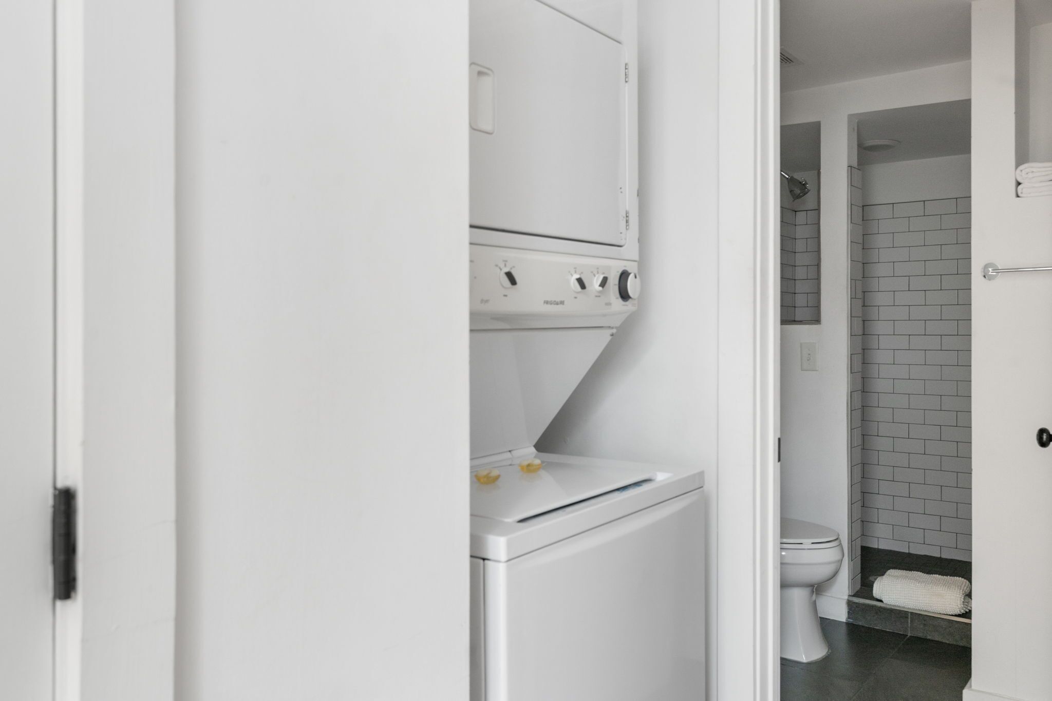 A modern bathroom with a white toilet, a glass shower enclosure, and a white washing machine.