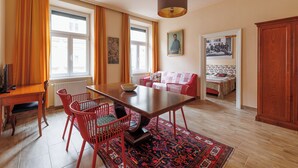 A dining area with a wooden table, red chairs, a rug, and a hanging light fixture. - Jugendstil Boutique Studio, 57 m², original art, central family hotel (Wien)
