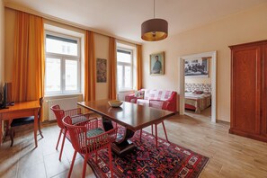 A dining area with a wooden table, red chairs, a rug, and a pendant light. - Artsy Boutique Studio, 57 m², Art Nouveau hotel, ideal for extended stays (Wien)