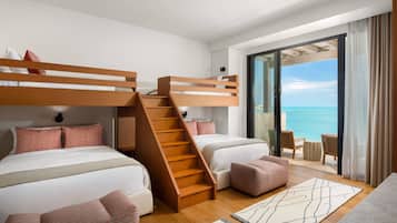 Une chambre d’hôtel moderne avec des lits superposés, un escalier, un balcon donnant sur la mer et un coin salon.