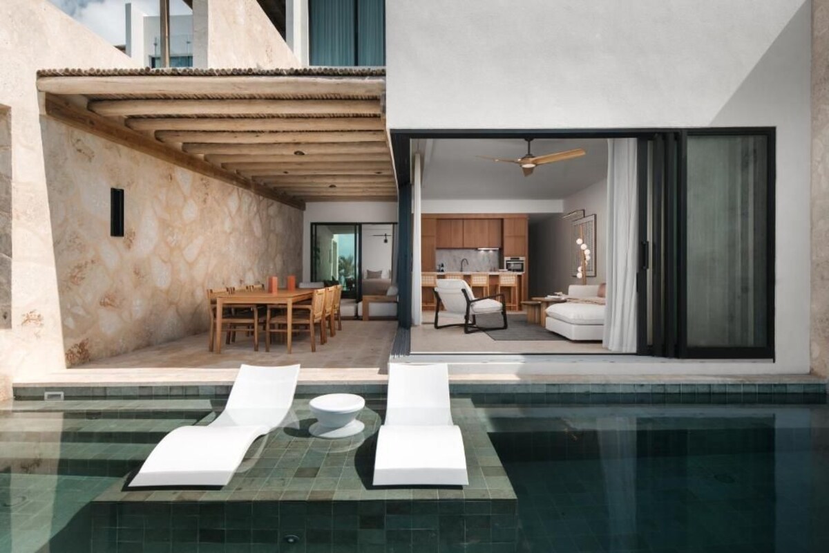 A modern outdoor pool area with lounge chairs and a dining set.