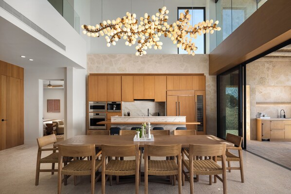 A modern kitchen with wooden cabinets, a central island, and a hanging light fixture.