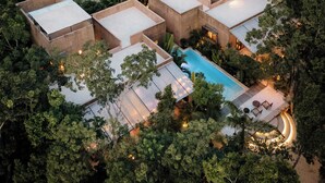 A modern, multi-story building with a swimming pool surrounded by lush greenery. - Villa Najil Chak Tulum : 16 Guests : Private Pool : Groups Retreats & Events (Tulum)