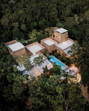 A modern, multi-story building with a swimming pool surrounded by lush greenery.
