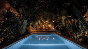 A nighttime pool area with a clear pool, surrounded by tropical plants and illuminated by hanging lanterns. - Villa Najil Chak Tulum : 16 Guests : Private Pool : Groups Retreats & Events (Tulum)