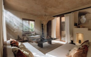 A spacious room with a large window, a woven ceiling light, a sofa, a coffee table, and a decorative vase.