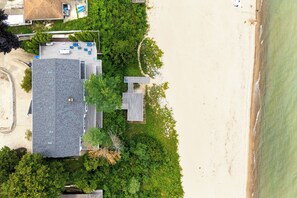An aerial view of a beachside property with a large house, a covered patio, and a sandy beach. - New Buffalo Sandcastle (New Buffalo)