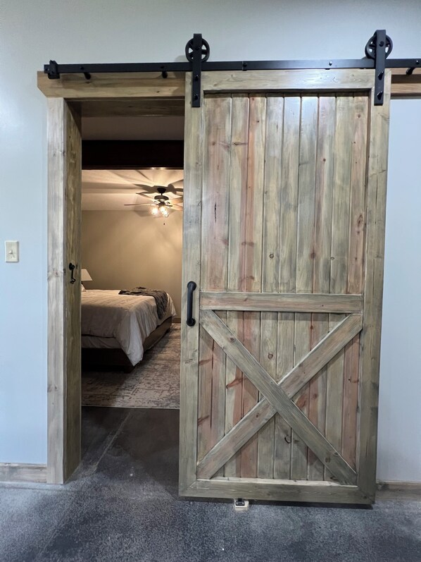 A room with a bed, a ceiling fan, and a carpeted floor.
