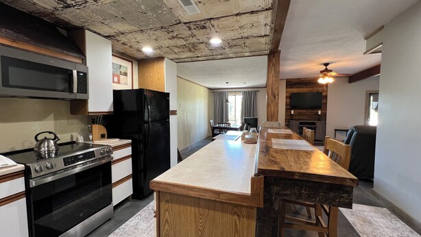 A kitchen with a wooden island, stainless steel appliances, and a rustic ceiling.