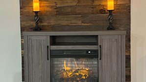 A fireplace with a modern design, flanked by two lit candles on stands.