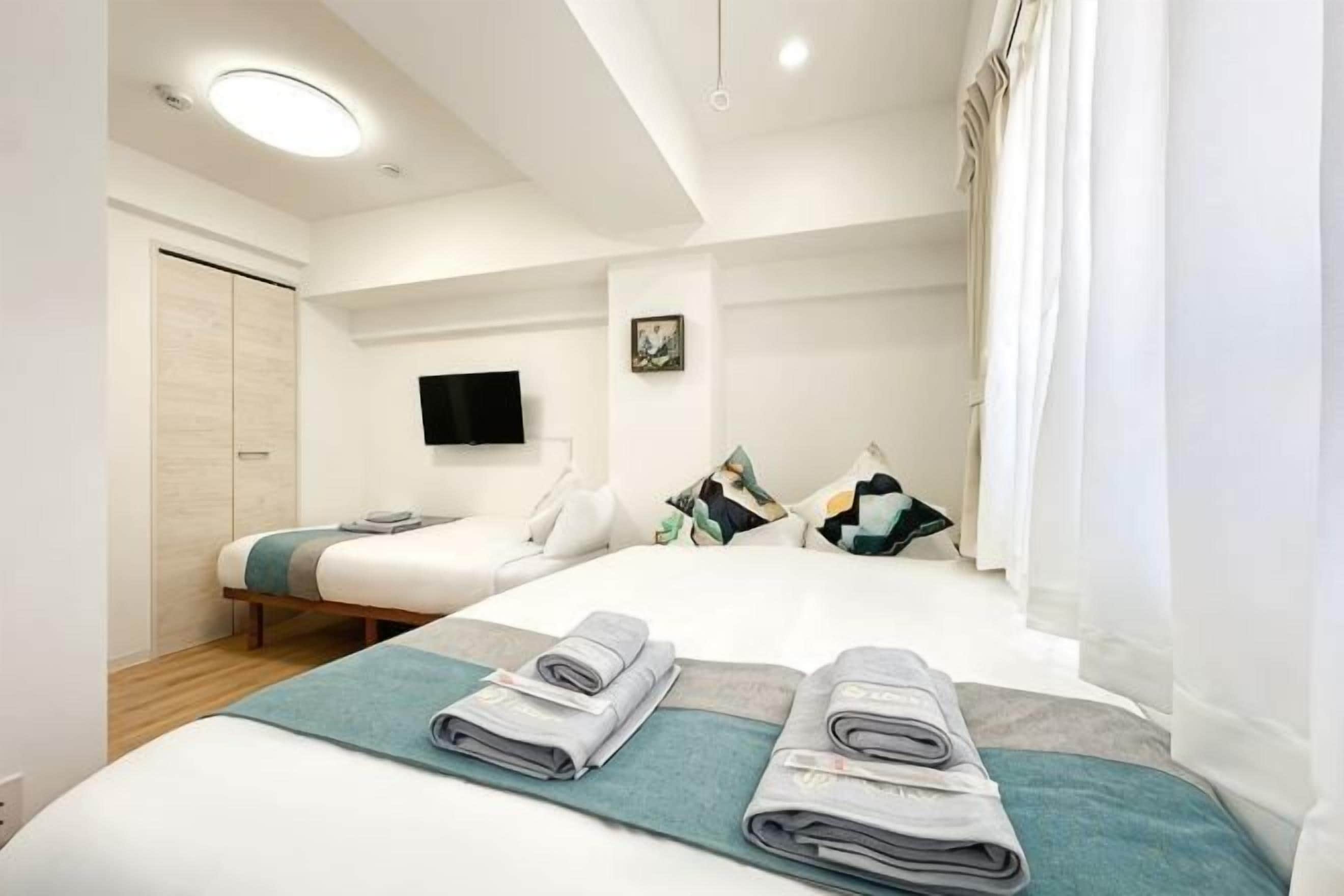 A hotel room with a bed, a TV, and a window with curtains.