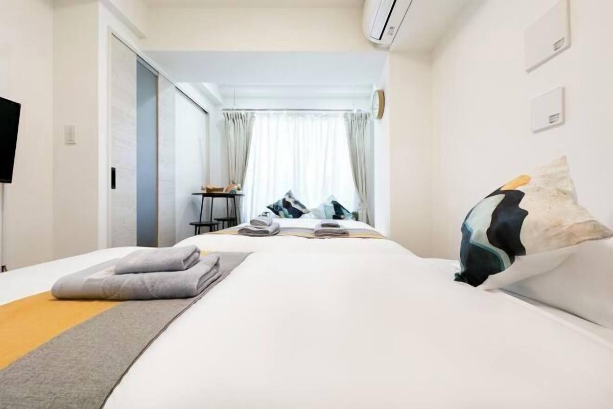 Een hotelkamer met een groot bed, een bureau en een stoel. Er is een raam met gordijnen, en de kamer heeft een modern design.