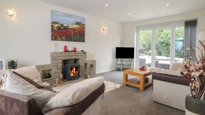A modern living room with a stone fireplace, a flat-screen TV, a sofa, and a dining table.