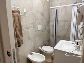 Un baño con lavamanos blanco, un bidé, un inodoro y un perchero para toallas.