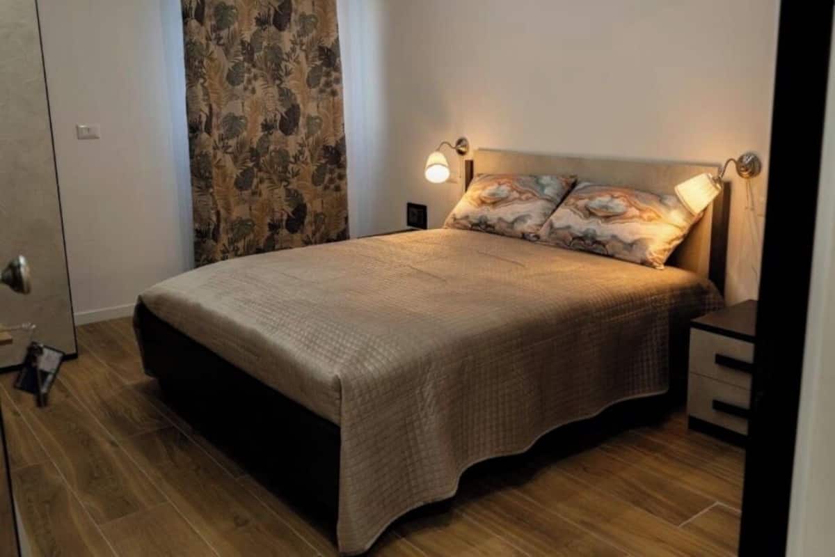 Ein Schlafzimmer mit Bett, Nachttischen, einer Lampe und einem Vorhang.