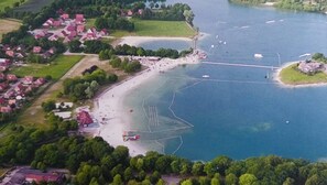 Vue aérienne d’une zone côtière avec une plage, des bateaux et un pont.