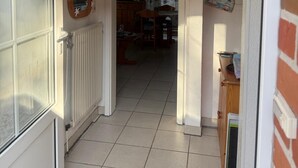 A hallway with a welcome sign, a mirror, and a door leading to a room with a tiled floor.