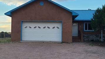 A single-story house with a brown exterior and a blue roof. It features a white garage door with decorative cutouts.