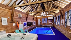 A hot tub and an indoor pool with wooden beams and a blue floor. - 1 Bed Cabin-sleeps 2, Hot Tub, Garden, Views, Pets (Callington)