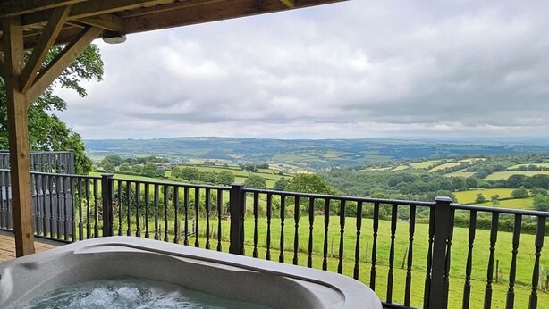 A hot tub with a view of rolling green hills and a cloudy sky. - 1 Bed Cabin-sleeps 2, Hot Tub, Garden, Views, Pets (Callington)