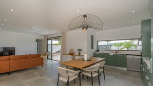 Una cocina moderna con comedor, que cuenta con una mesa y sillas de madera, un ventilador de techo y vistas al exterior.