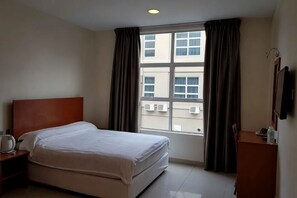 A hotel room with a bed, a nightstand, a desk, a window with curtains, and a wall-mounted TV. - Aeton Hotel Nilai (Nilai)