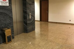 Un pasillo con piso de mármol, una puerta y un cartel que indica prohibido fumar.