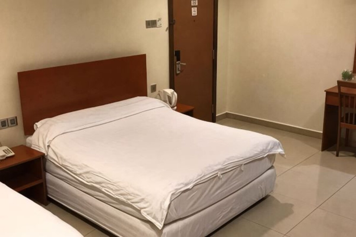A hotel room with a bed, bedside table, and a door.