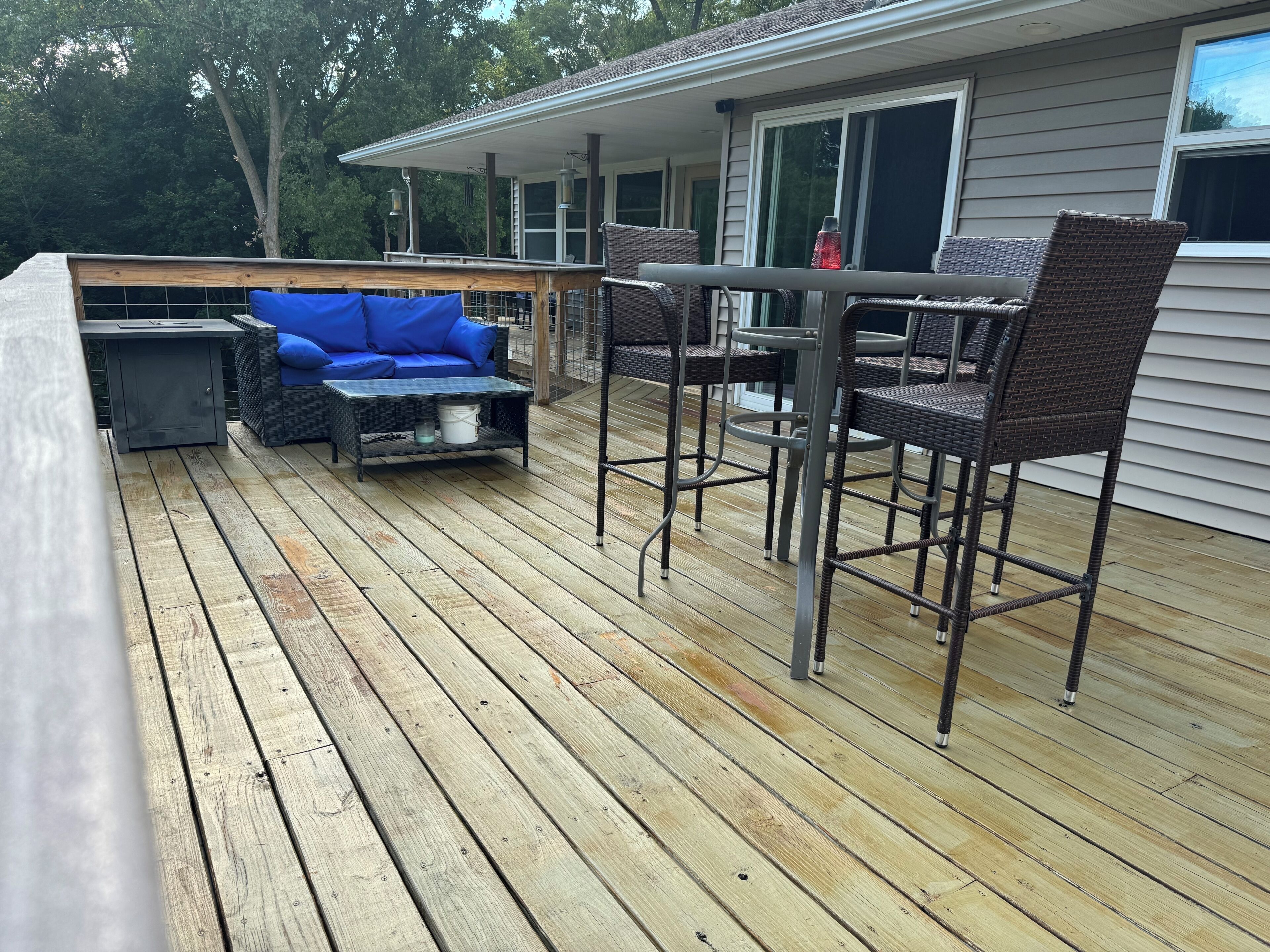 A wooden deck with outdoor furniture, including a sofa and chairs, and a table.